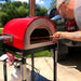 WPPO Traditional Red 25-Inch Dual Fueled Pizza Oven With Gas Attachment | Shown Cooking Outside
