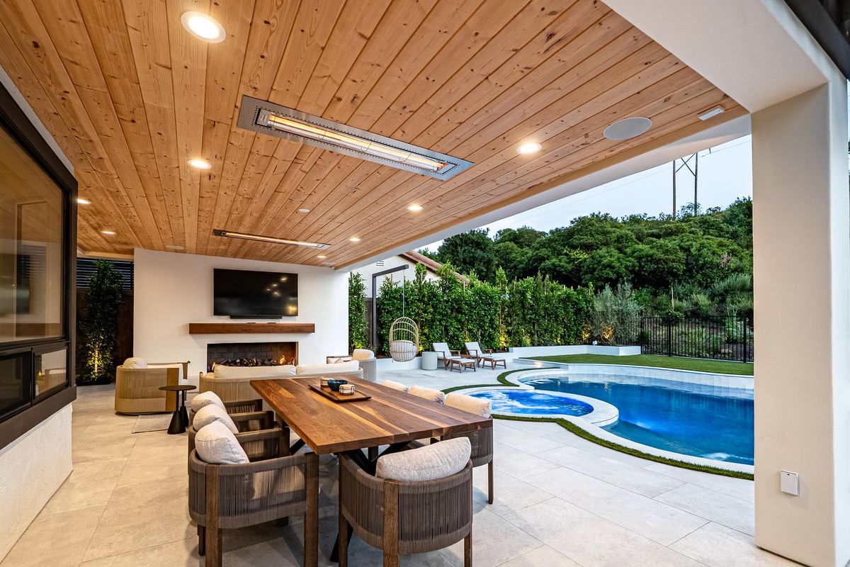 Two flush mount Infratech heaters recessed into a wood patio ceiling over an outdoor dining area, fireplace and pool
