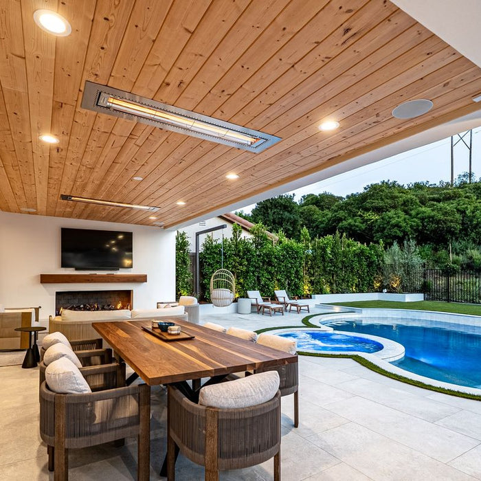 Two flush mount Infratech heaters recessed into a wood patio ceiling over an outdoor dining area, fireplace and pool