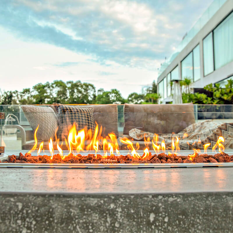 Elementi 55 Inch Hampton Rectangular Concrete Fire Table in Light Gray On Patio with Wind Guard