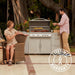 Couple entertaining beside a Blaze LTE+ 32 inch built-in gas grill outdoor kitchen