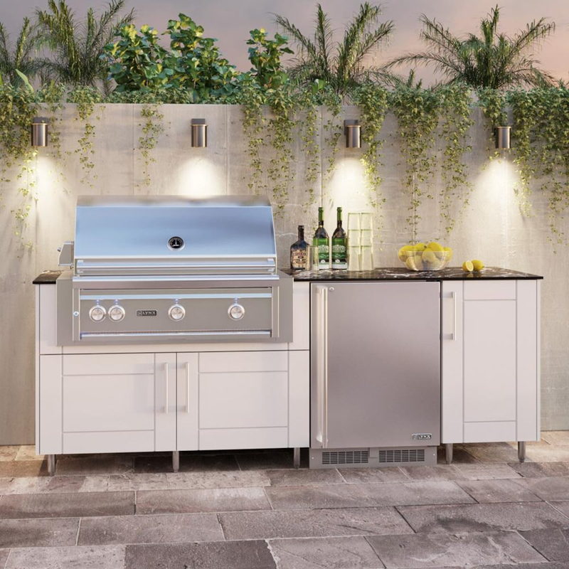 WeatherStrong Bimini Shell White outdoor kitchen island with Blaze grill and refrigerator lit at dusk