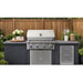 Wildfire Ember 32-inch stainless steel gas grill built into a grey outdoor kitchen island against a wood fence.