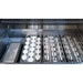 Close-up inside the Wildfire Ember gas grill showing ceramic briquette trays beside stainless steel cooking grates.