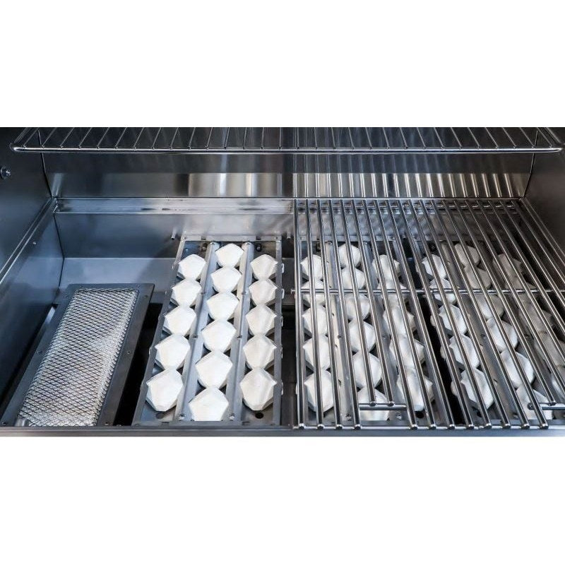 Close-up inside the Wildfire Ember gas grill showing ceramic briquette trays beside stainless steel cooking grates.
